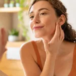 Woman looking in mirror trying to figure out how to prevent ozempic face during weight loss